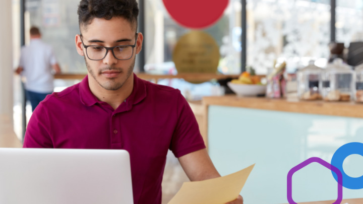 Man looking at laptop and piece of paper