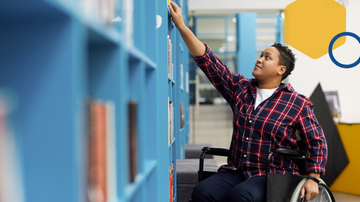 Student reaching for books in library.